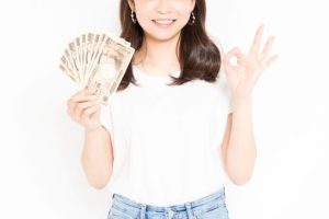 お札とOKサインをする女性