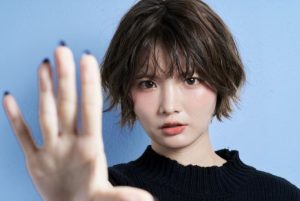 こちらに手のひらを向けて止める女性